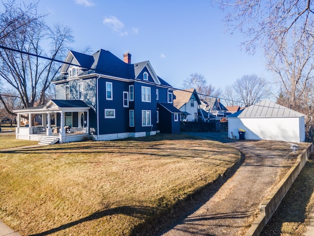 rear view of property featuring covered porch and a yard