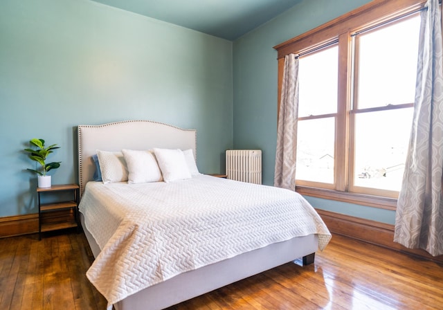 bedroom with radiator and dark hardwood / wood-style flooring