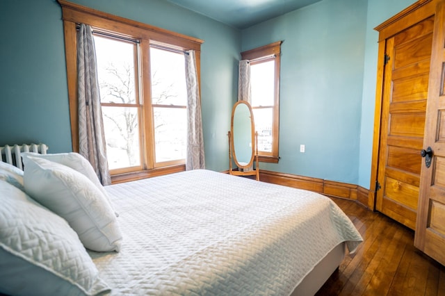 bedroom with dark hardwood / wood-style flooring and radiator