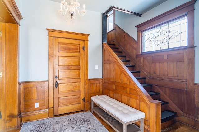 118 Chestnut St, Lake City, MN 55041 - foyer entrance featuring stairway, a chandelier, wood finished floors, a wainscoted wall, and wooden walls