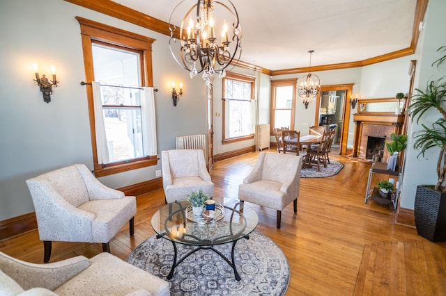 living area featuring light hardwood / wood-style floors, ornamental molding, and a brick fireplace