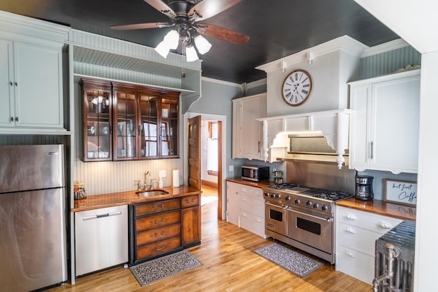 kitchen with stainless steel appliances, white cabinetry, ceiling fan, and ornamental molding