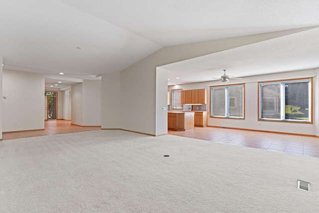 unfurnished living room with ceiling fan, light colored carpet, and vaulted ceiling