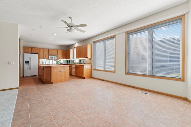 kitchen featuring light tile patterned floors, white appliances, a kitchen island, and ceiling fan