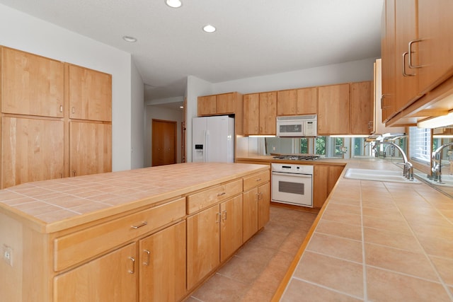 kitchen with tile countertops, white appliances, sink, light tile patterned floors, and a kitchen island