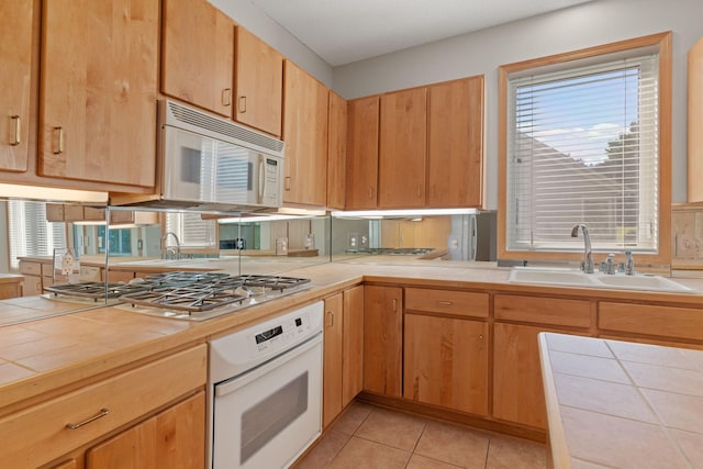 kitchen featuring light tile patterned floors, white appliances, tile countertops, and sink