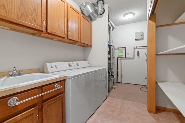 laundry room featuring washer and clothes dryer, cabinets, sink, light tile patterned floors, and a textured ceiling