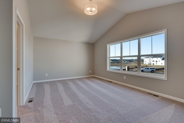 carpeted empty room featuring lofted ceiling