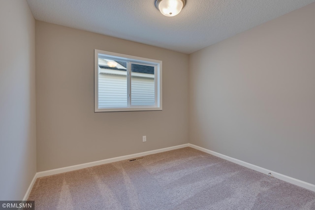 carpeted empty room featuring a textured ceiling