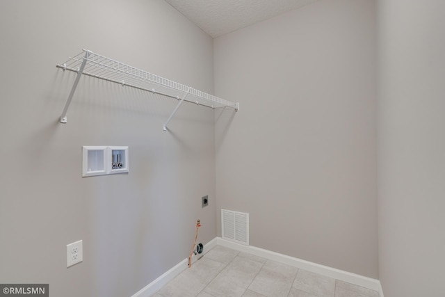 clothes washing area featuring washer hookup, a textured ceiling, gas dryer hookup, and electric dryer hookup