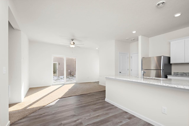 kitchen with light stone countertops, ceiling fan, light hardwood / wood-style flooring, stainless steel fridge, and white cabinets