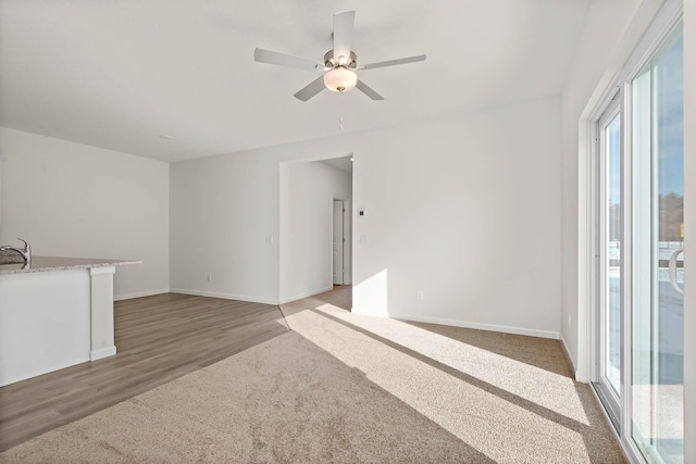 unfurnished living room with ceiling fan, sink, and dark colored carpet