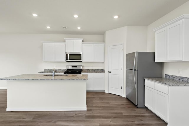 kitchen with white cabinetry, a center island with sink, light stone countertops, and appliances with stainless steel finishes