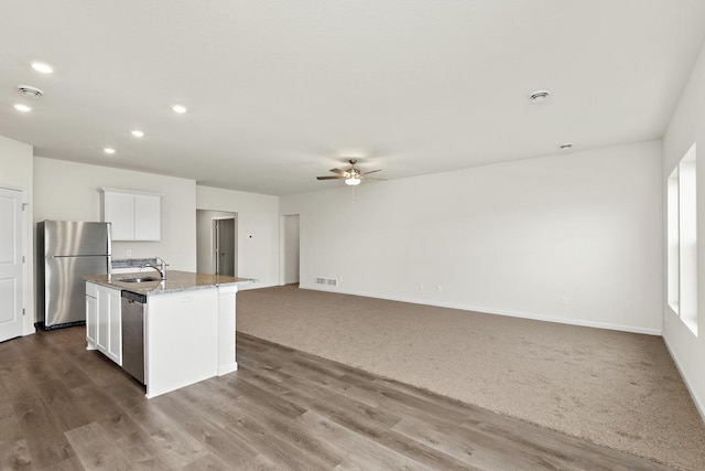 kitchen with ceiling fan, sink, stainless steel appliances, a center island with sink, and white cabinets