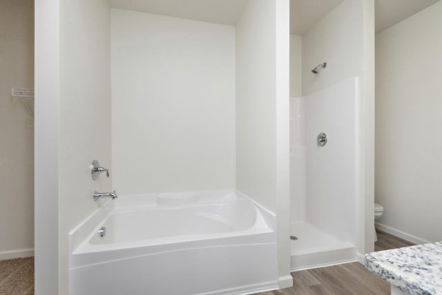 bathroom with plus walk in shower, hardwood / wood-style flooring, and toilet