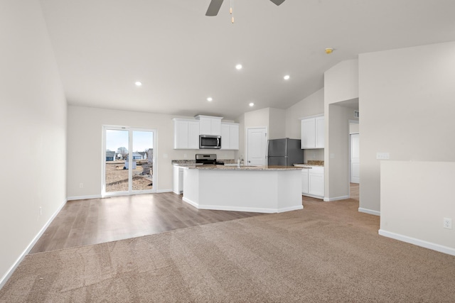 kitchen featuring ceiling fan, an island with sink, appliances with stainless steel finishes, light colored carpet, and white cabinetry