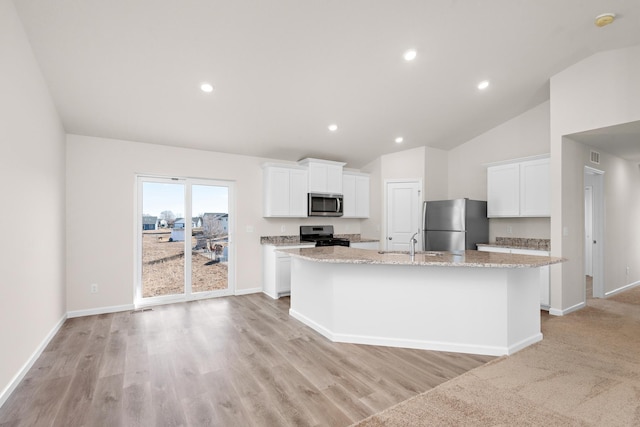 kitchen featuring appliances with stainless steel finishes, light stone counters, sink, a center island with sink, and white cabinetry