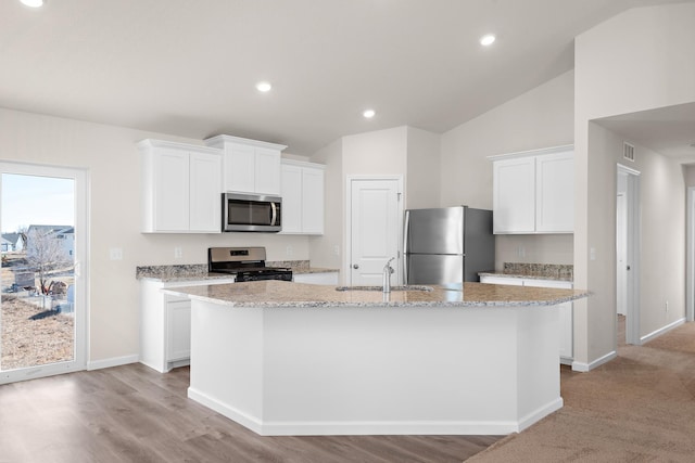 kitchen with white cabinets, sink, an island with sink, appliances with stainless steel finishes, and light stone counters