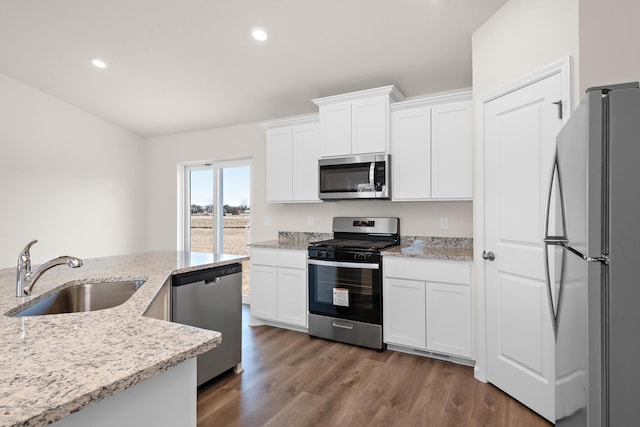 kitchen with white cabinets, appliances with stainless steel finishes, light stone countertops, and sink