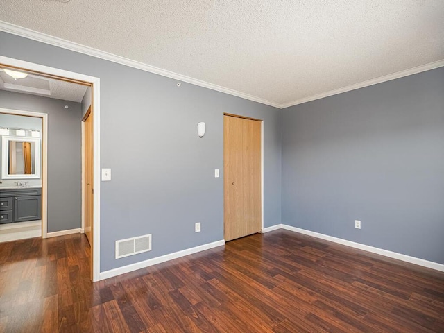 spare room featuring a textured ceiling, crown molding, and dark wood-type flooring