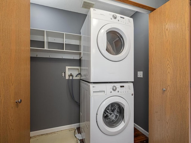 clothes washing area featuring stacked washing maching and dryer