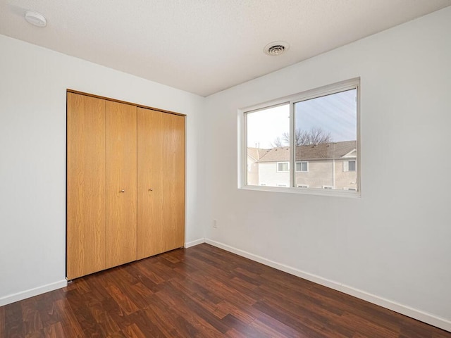 unfurnished bedroom with a closet and dark hardwood / wood-style flooring