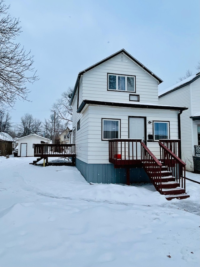 snow covered property with a garage and an outdoor structure