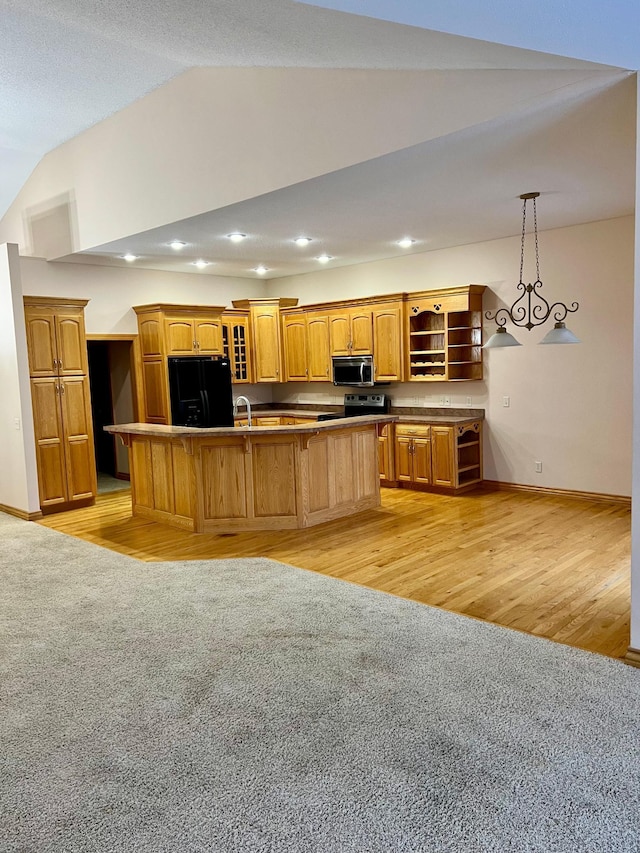 kitchen featuring black fridge with ice dispenser, a center island, vaulted ceiling, hanging light fixtures, and range with electric stovetop