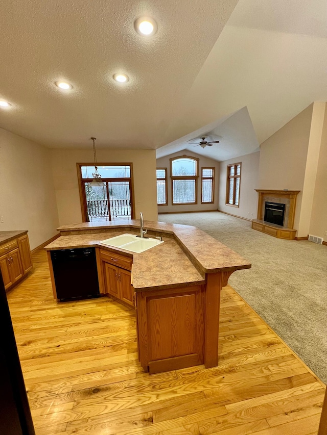 kitchen featuring sink, an island with sink, dishwasher, and vaulted ceiling