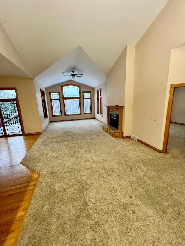 unfurnished living room featuring lofted ceiling, a tile fireplace, ceiling fan, and carpet