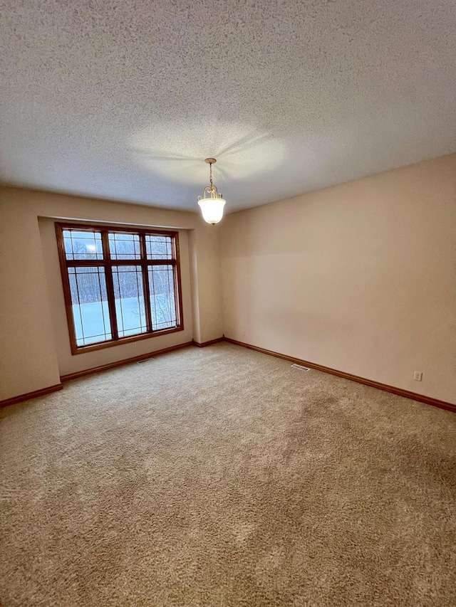 unfurnished room featuring carpet floors, a chandelier, and a textured ceiling