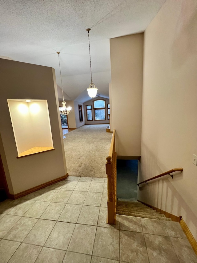 staircase featuring carpet flooring, a textured ceiling, vaulted ceiling, and a notable chandelier