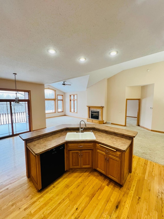 kitchen with dishwasher, vaulted ceiling, a textured ceiling, sink, and light hardwood / wood-style flooring