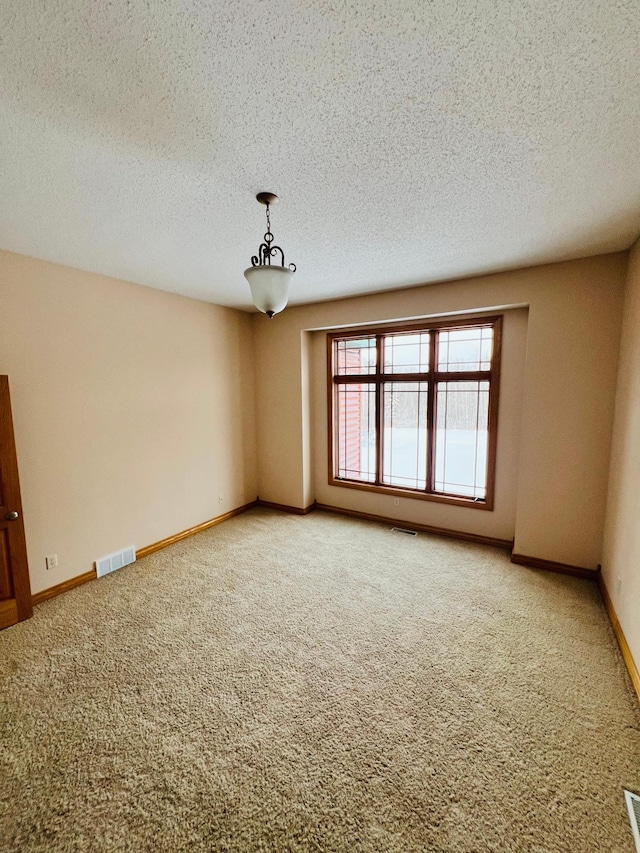 carpeted empty room with a textured ceiling