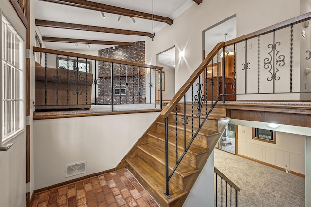 staircase featuring beamed ceiling