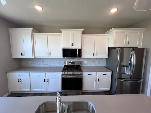 kitchen featuring decorative backsplash, white cabinets, and appliances with stainless steel finishes