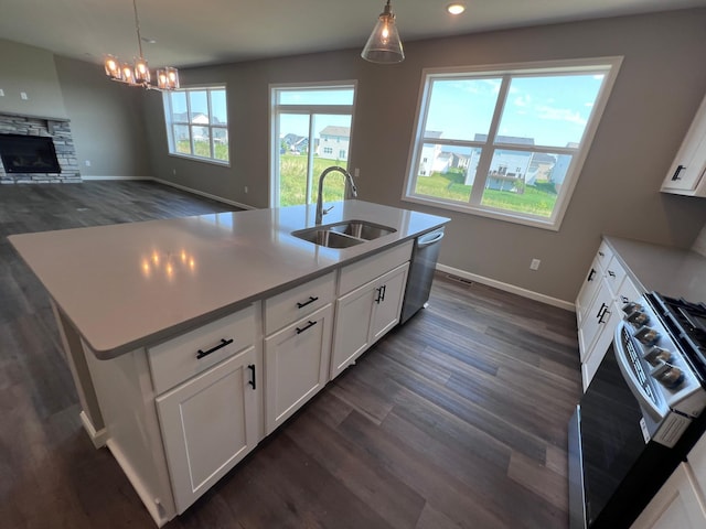 kitchen with hanging light fixtures, white cabinetry, sink, and a kitchen island with sink