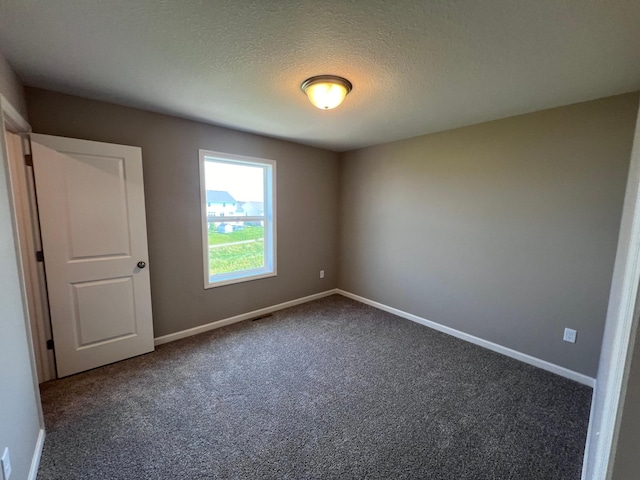 empty room featuring dark colored carpet and a textured ceiling