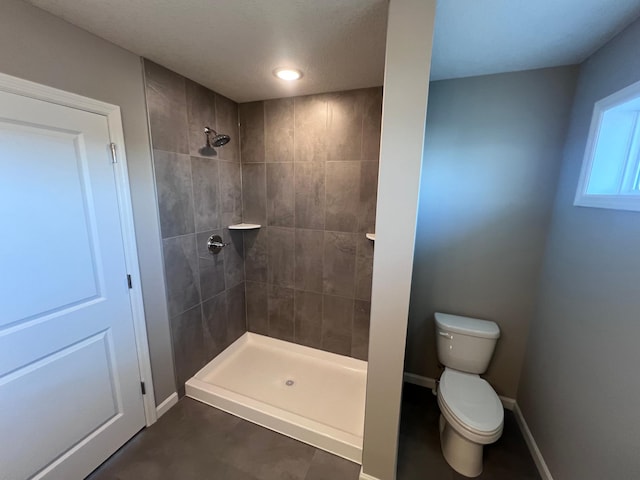 bathroom featuring a tile shower and toilet