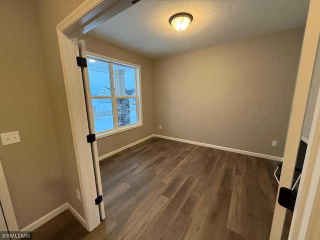 spare room with a textured ceiling and dark hardwood / wood-style flooring