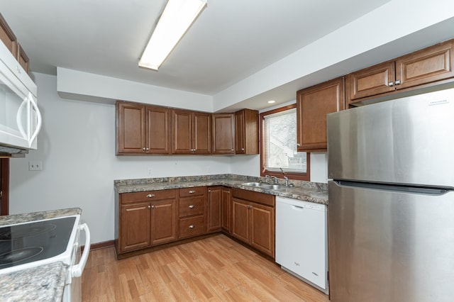 kitchen with light stone countertops, white appliances, light hardwood / wood-style floors, and sink