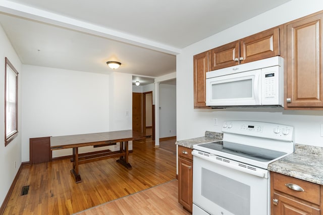 kitchen featuring light stone countertops, light hardwood / wood-style floors, and white appliances