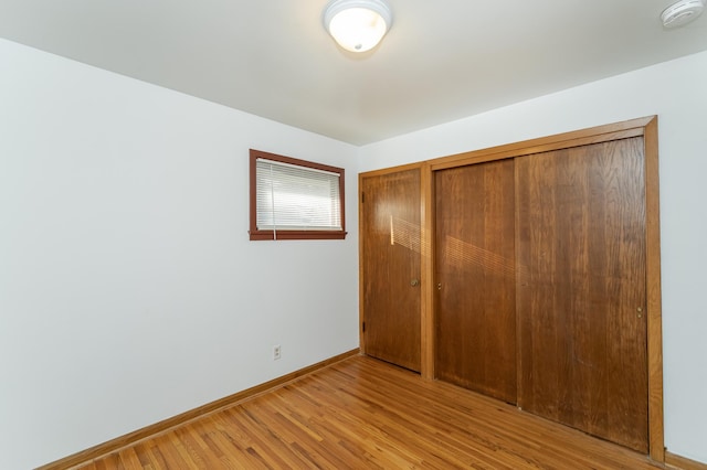 unfurnished bedroom with light wood-type flooring and a closet