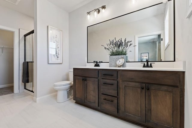 bathroom with a shower with door, vanity, and toilet