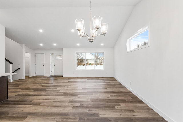 unfurnished living room with a chandelier, dark wood-type flooring, plenty of natural light, and lofted ceiling