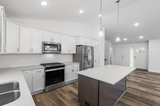 kitchen with a center island, hanging light fixtures, vaulted ceiling, appliances with stainless steel finishes, and white cabinetry