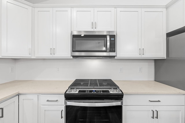 kitchen featuring light stone counters, white cabinets, and stainless steel appliances