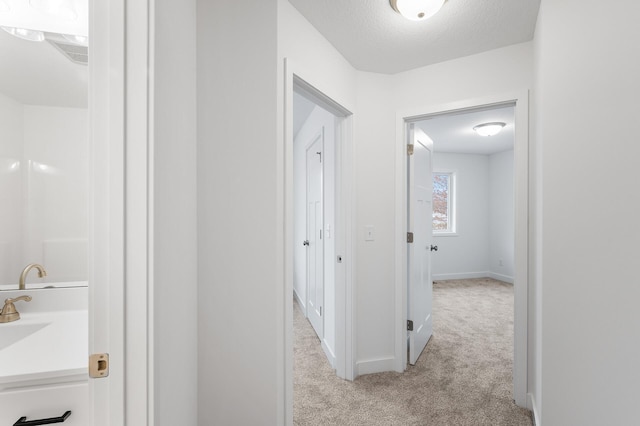 hall with light carpet and a textured ceiling