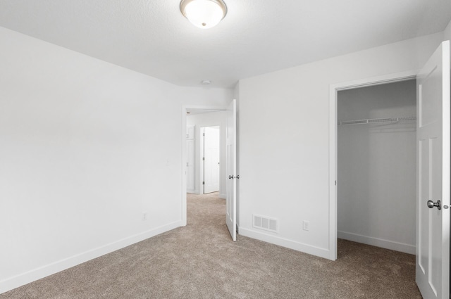 unfurnished bedroom featuring light colored carpet and a closet