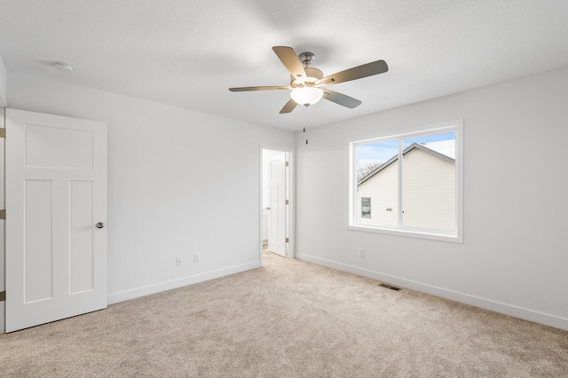 carpeted spare room featuring ceiling fan, a textured ceiling, visible vents, and baseboards